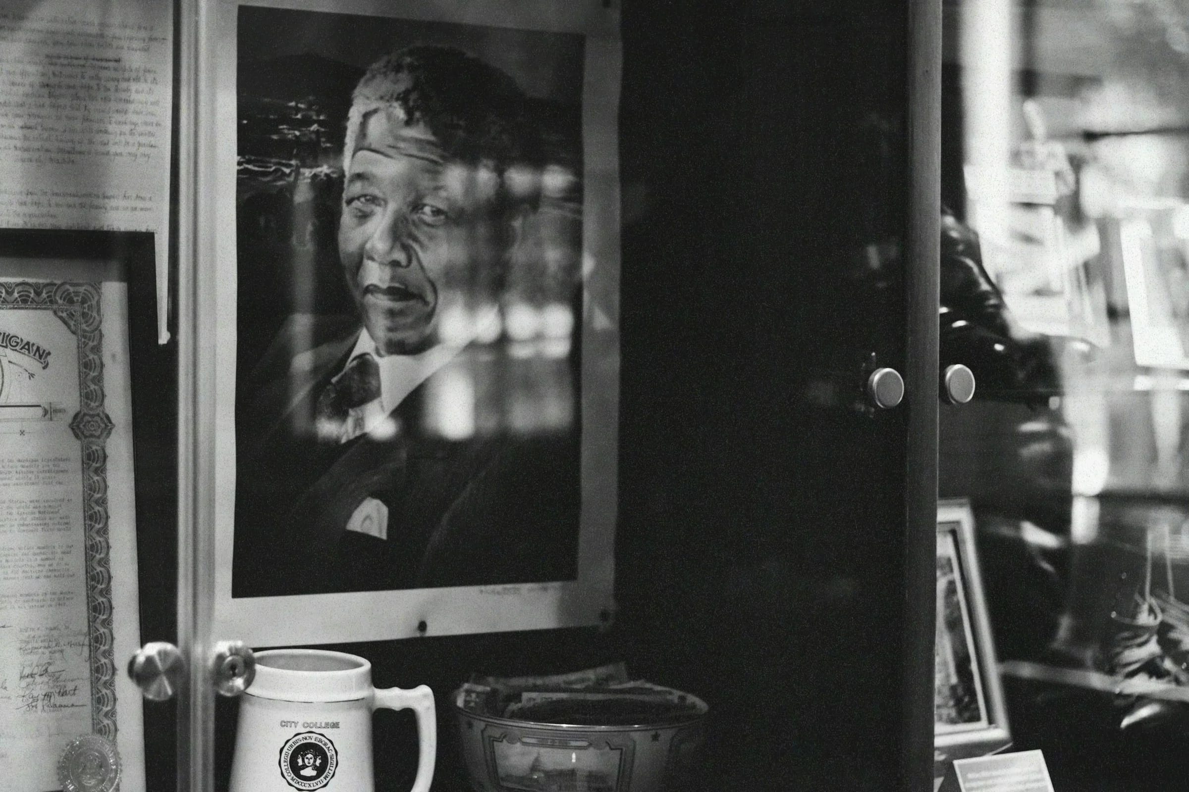 Man reflected beside a Mandela portrait inside a Houghton café